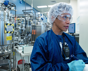 Genentech employee with lab coat, gloves, and goggles